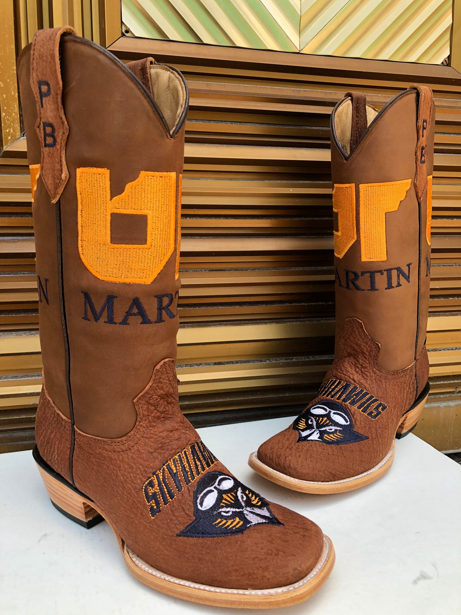 A pair of custom shark skin boots with the University of Tennesse at Martin Custom logo and the Skyhawks mascot stitched on